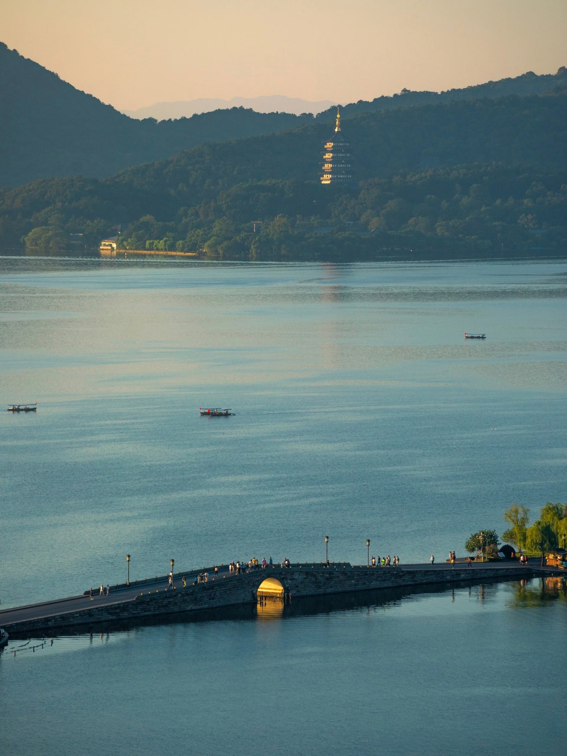 West Lake at sunrise, mist on the water, morning light from the Su Causeway